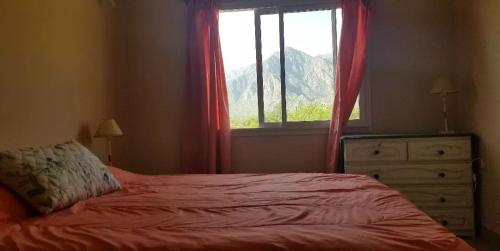 a bedroom with a bed and a window and a dresser at Cabañas Cafayate in Cafayate