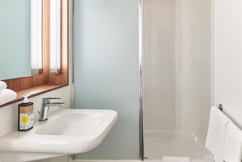 a bathroom with a sink and a shower at Greet Hotel Versailles - Voisins Le Bretonneux in Voisins-le-Bretonneux