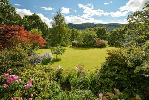 a garden with a lawn with trees and flowers at Wintergreen in Pitlochry