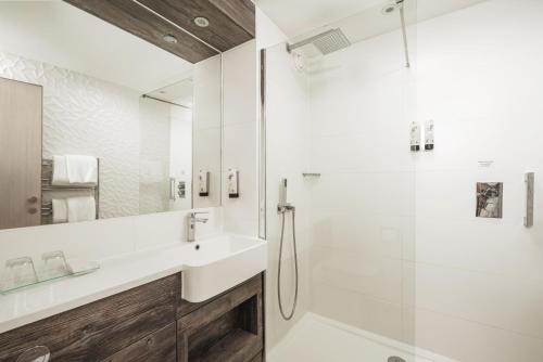 a white bathroom with a sink and a shower at The Waterfront Hotel Spa & Golf in Saint Neots