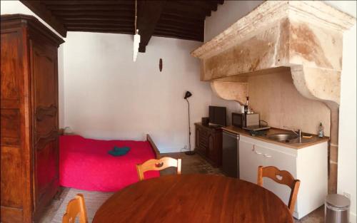 Zimmer mit einem Tisch und einer Küche mit einem roten Teppich in der Unterkunft Joli studio de caractère in Gray