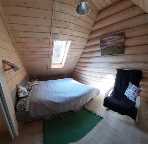 1 dormitorio en una cabaña de madera con 1 cama y 1 silla en Chatka pod lasem Bezpłatne Jacuzzi en Szczyrk