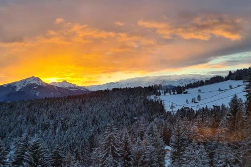 a sunset over a snowy mountain with trees and mountains at Haughof Apartement Blumenwiese in Verano