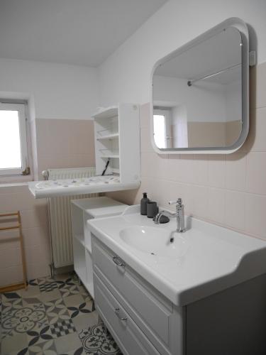 a white bathroom with a sink and a mirror at Gîte Madeleine et Clémentine in Gueberschwihr