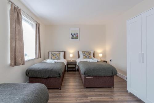 sypialnia z 2 łóżkami pojedynczymi i oknem w obiekcie Beautiful 2-Bed House in quiet cul-de-sac w mieście Barking