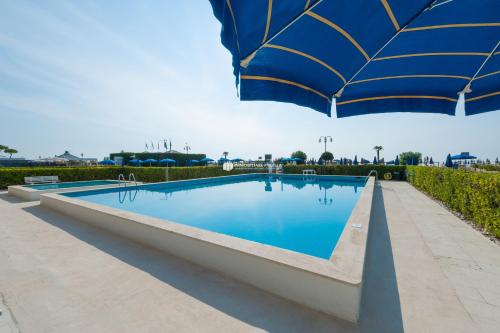 una grande piscina blu con ombrellone di Residence Zeta Immobiliare Pacella a Lido di Jesolo