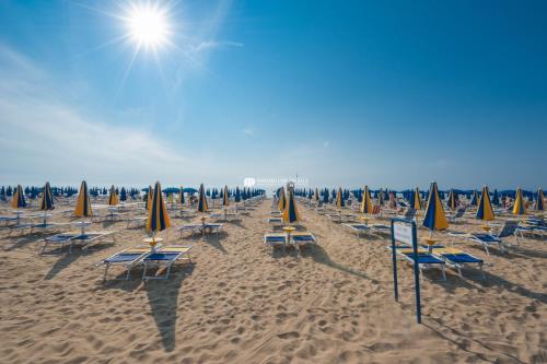 una fila di sedie e ombrelloni in spiaggia di Residence Zeta Immobiliare Pacella a Lido di Jesolo