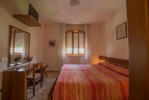 a bedroom with a bed and a desk and windows at Hotel Santa Maria in Assisi