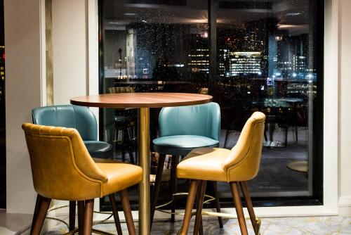 a table and chairs in front of a window at Crowne Plaza Manchester City Centre by IHG in Manchester