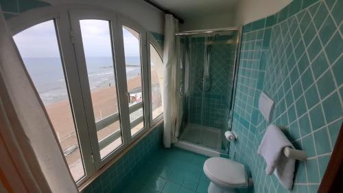 a bathroom with a toilet and a window with the beach at Casa Vacanze Elianto in Anzio