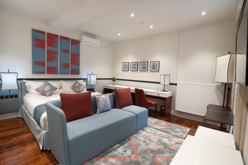 a bedroom with a bed and a couch and a desk at Somerset City Centre Atyrau in Atyraū