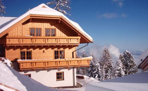 a wooden building with a balcony in the snow at Almhaus Karantanien in Hochrindl
