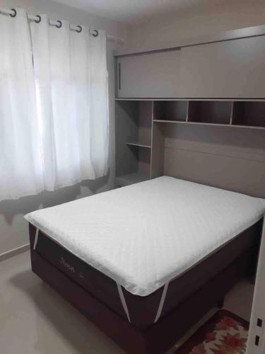 a bed sitting in a bedroom next to a window at Apto excelente à 50m do parque de águas termais in Piratuba