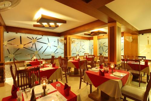 a restaurant with red tables and chairs and a large window at Hotel Pearl Palace in Cochin