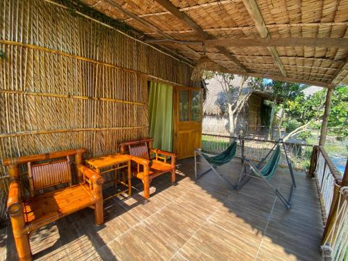 a porch with two benches and a hammock on it at Green Village Mekong in Can Tho