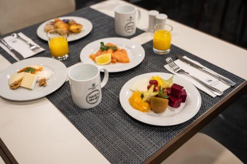 einen Tisch mit Teller mit Lebensmitteln und Tassen Orangensaft in der Unterkunft Eurostars Das Letras in Lissabon