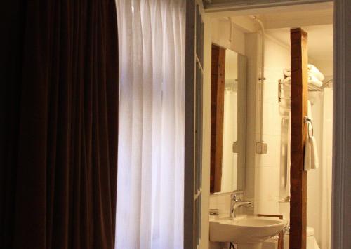 a bathroom with a white shower curtain and a sink at Hotel Boutique Casa Conde in Santiago