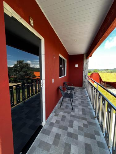 a balcony with a bench and a red wall at Pousada Encanto dos Anjos in Pirenópolis