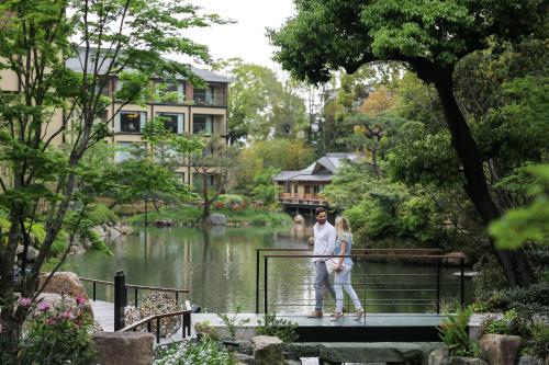 a woman walking down a river next to a dock at Four Seasons Hotel Kyoto in Kyoto