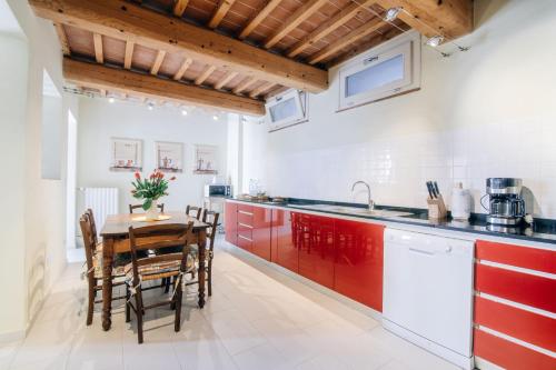 UzzanoにあるHoliday Home Il Borgo Degli Agrumiのキッチン(赤いキャビネット、テーブル、椅子付)
