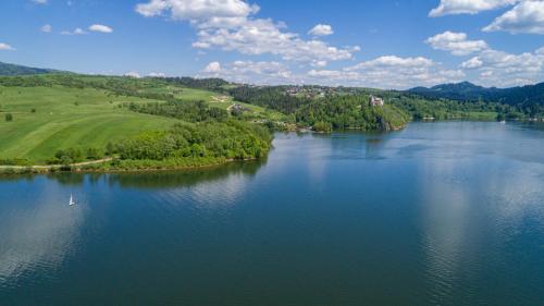 an aerial view of a lake with trees and a field at FAJNE CHATY - rodzinny wypoczynek w górach in Falsztyn