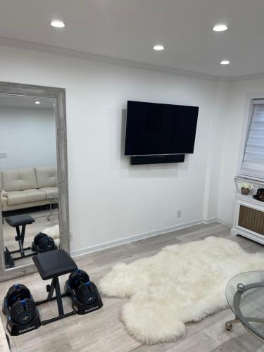 a living room with a television on a wall at Renovated Jacuzzi Tub Home NYC-LGA-JFK Washer-Dryer in Kew Gardens