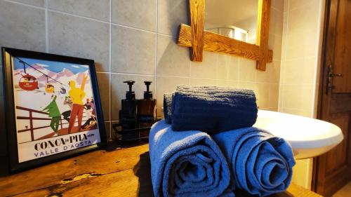 y baño con toallas azules, lavabo y espejo. en Chalet Saint Salod - Pila, en Charvensod