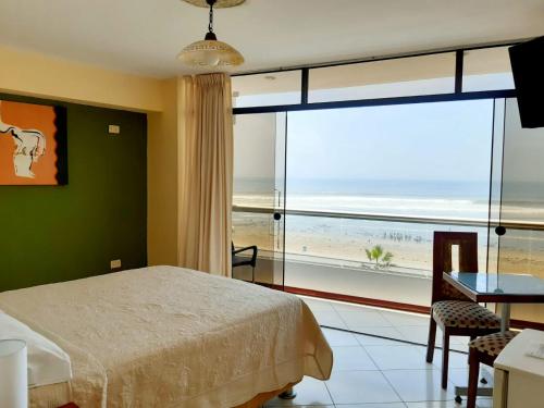 a bedroom with a bed and a view of the beach at Hotel Huankarute in Huanchaco