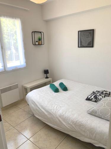 une chambre avec un lit avec deux oreillers dessus dans l'établissement Maison T4 -Jardin+ Parking+ Clim -Proche Remparts, à Aigues-Mortes