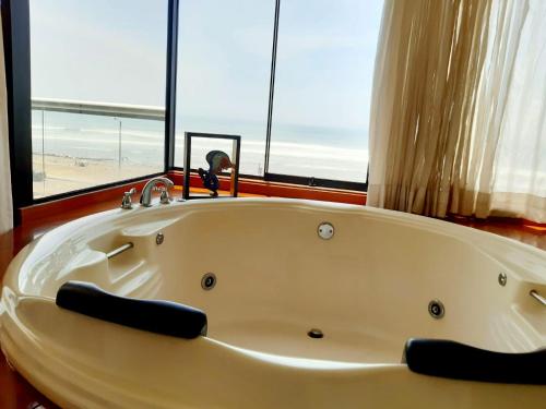 a white bath tub in a room with a window at Hotel Huankarute in Huanchaco