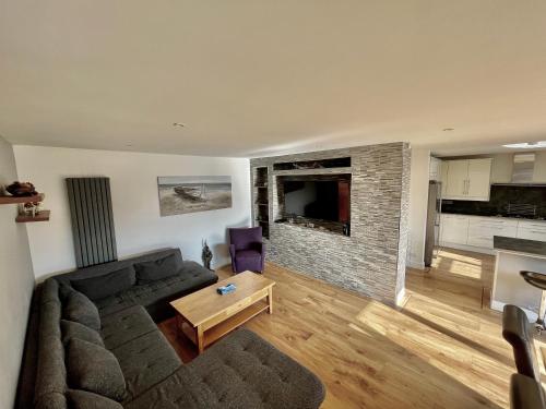a living room with a couch and a brick fireplace at Four Corners Holiday Home Hot Tub & Sauna in Ferndown