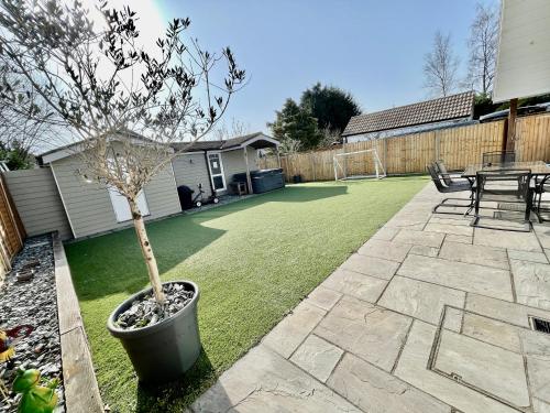a small tree in a pot on a lawn at Four Corners Holiday Home Hot Tub & Sauna in Ferndown