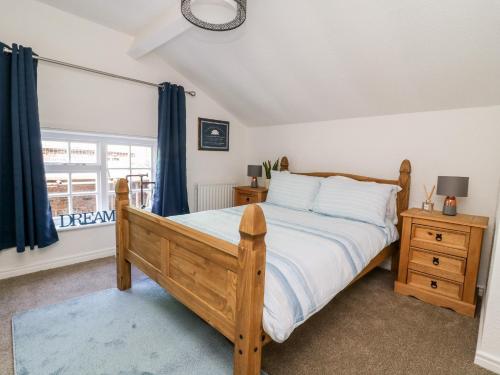 a bedroom with a wooden bed and a window at Ickle Pickle Cottage in Thirsk