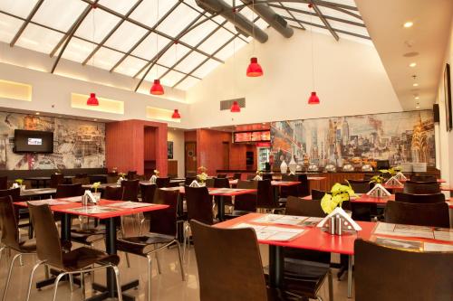 新德里Red Fox by Lemon Tree Hotels, East Delhi的摆着红色桌椅的餐厅