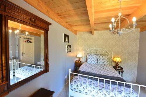 1 dormitorio con cama y espejo en Chez Pique-Fesse Chambre d'hote, en Saint-Martin-lʼArs