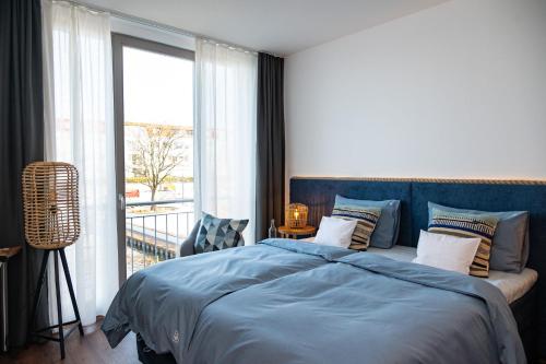 a bedroom with a blue bed and a balcony at Hafenmeisterei in Steinhude