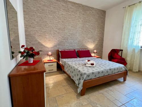 una camera da letto con un letto con cuscini rossi di Villetta Girasole a Marina di Mancaversa