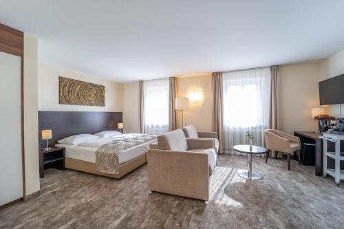バートライヘンハルにあるGalerie Hotelのベッド、ソファ、椅子が備わるホテルルームです。