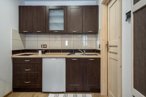 a kitchen with wooden cabinets and a white dishwasher at Domek u Świerków in Chochołów