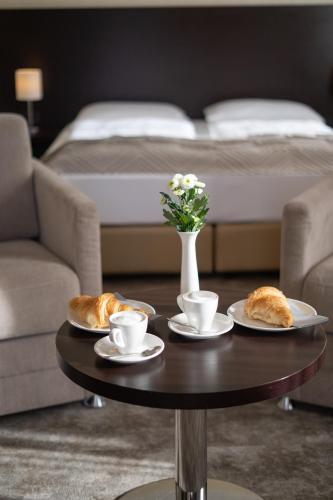 a coffee table with croissants and cups and a bed at Galerie Hotel in Bad Reichenhall