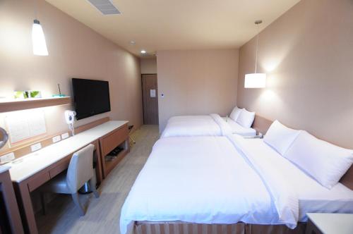 a hotel room with two beds and a desk at Kindness Hotel - Tainan Chihkan Tower in Tainan