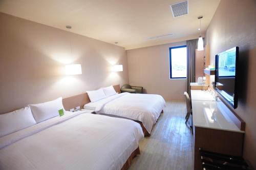 a hotel room with two beds and a flat screen tv at Kindness Hotel - Tainan Chihkan Tower in Tainan