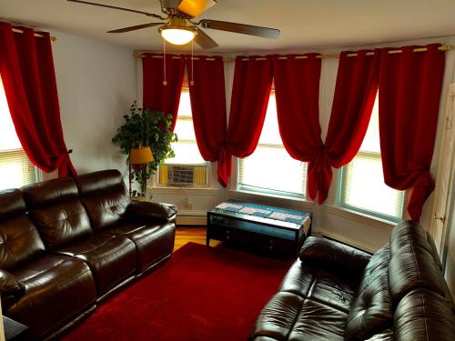 a living room with two leather couches and red curtains at Stylish, Cozy 2BR Private Apt, 1st Floor, Well-Appointed, Near Providence, MA, RI Line, I-95 Access in Pawtucket