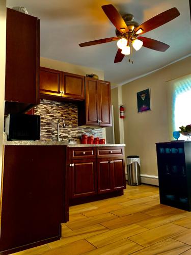 a kitchen with wooden cabinets and a ceiling fan at Stylish, Cozy 2BR Private Apt, 1st Floor, Well-Appointed, Near Providence, MA, RI Line, I-95 Access in Pawtucket