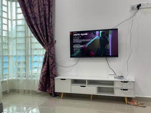 a living room with a tv on a white wall at Arwaa Homestay Beachview in Bachok