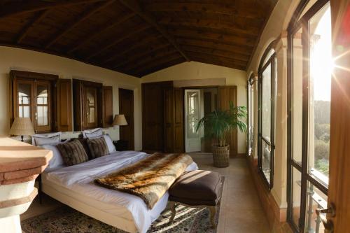 a bedroom with a large bed in a room with windows at Quinta da Bella Vista - Historic Home and Farm in Sintra