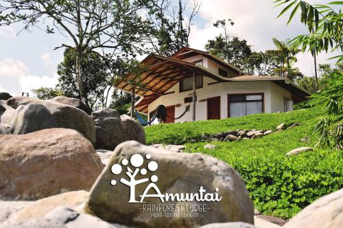 a house on a hill with rocks in front of a house at AMUNTAI RAINFOREST LODGE in Palora