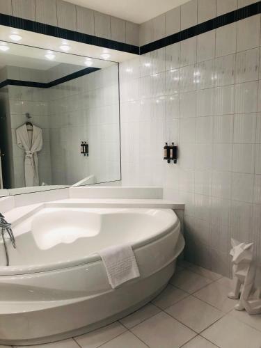 une baignoire blanche dans une salle de bain avec un miroir dans l'établissement Hotel Restaurant Chavant, à Bresson
