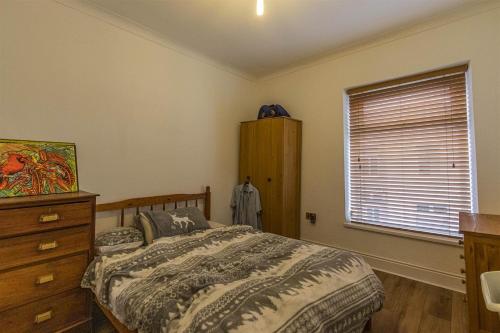 a bedroom with a bed and a dresser and a window at millennium stadium guest house in Cardiff
