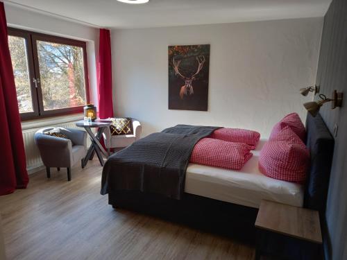 a bedroom with a bed with red pillows and a table at Hotel Engelbracht inklusive MeineCardPlus in Willingen